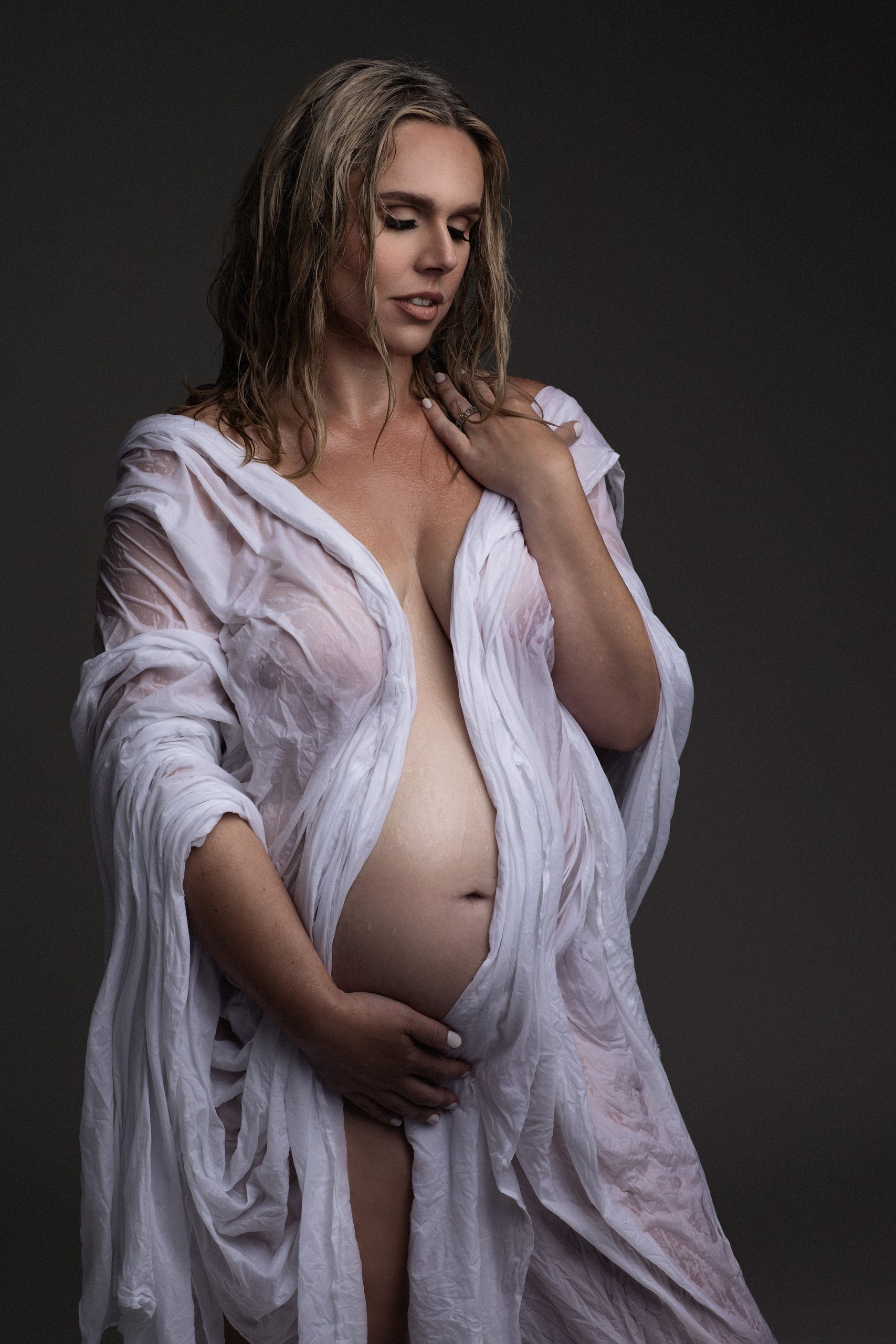 mom to be in white draped sheet holding her bump