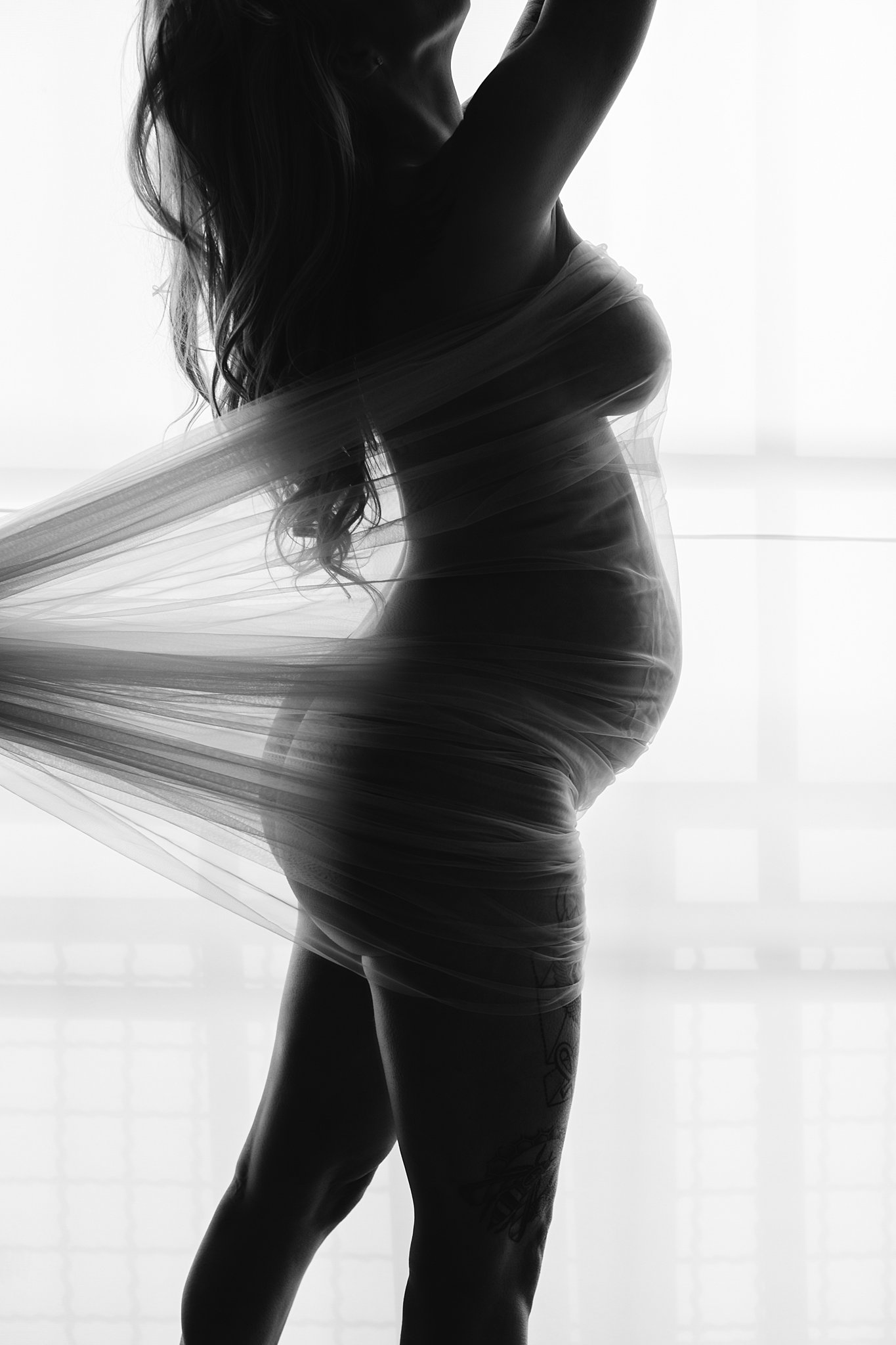 pregnant woman wrapped in a sheer cloth pulled behind her