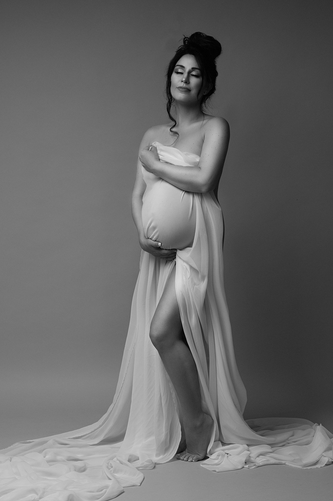 mom to be draped in cloth cradling her bump Maternity Stores in Atlanta
