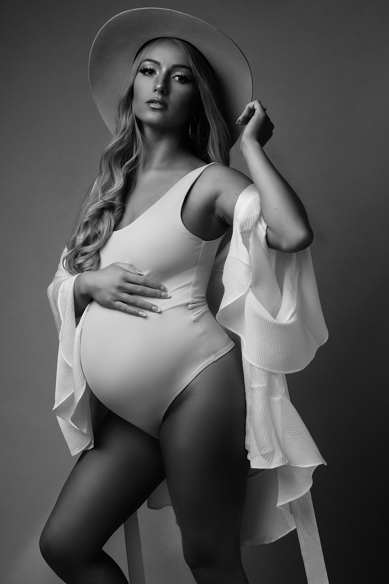 woman in light bodysuit with her hand on her baby bump