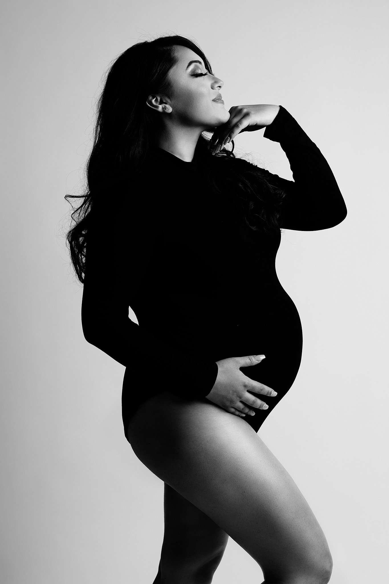 pregnant woman in black bodysuit cradling her bump Miami Prenatal Yoga