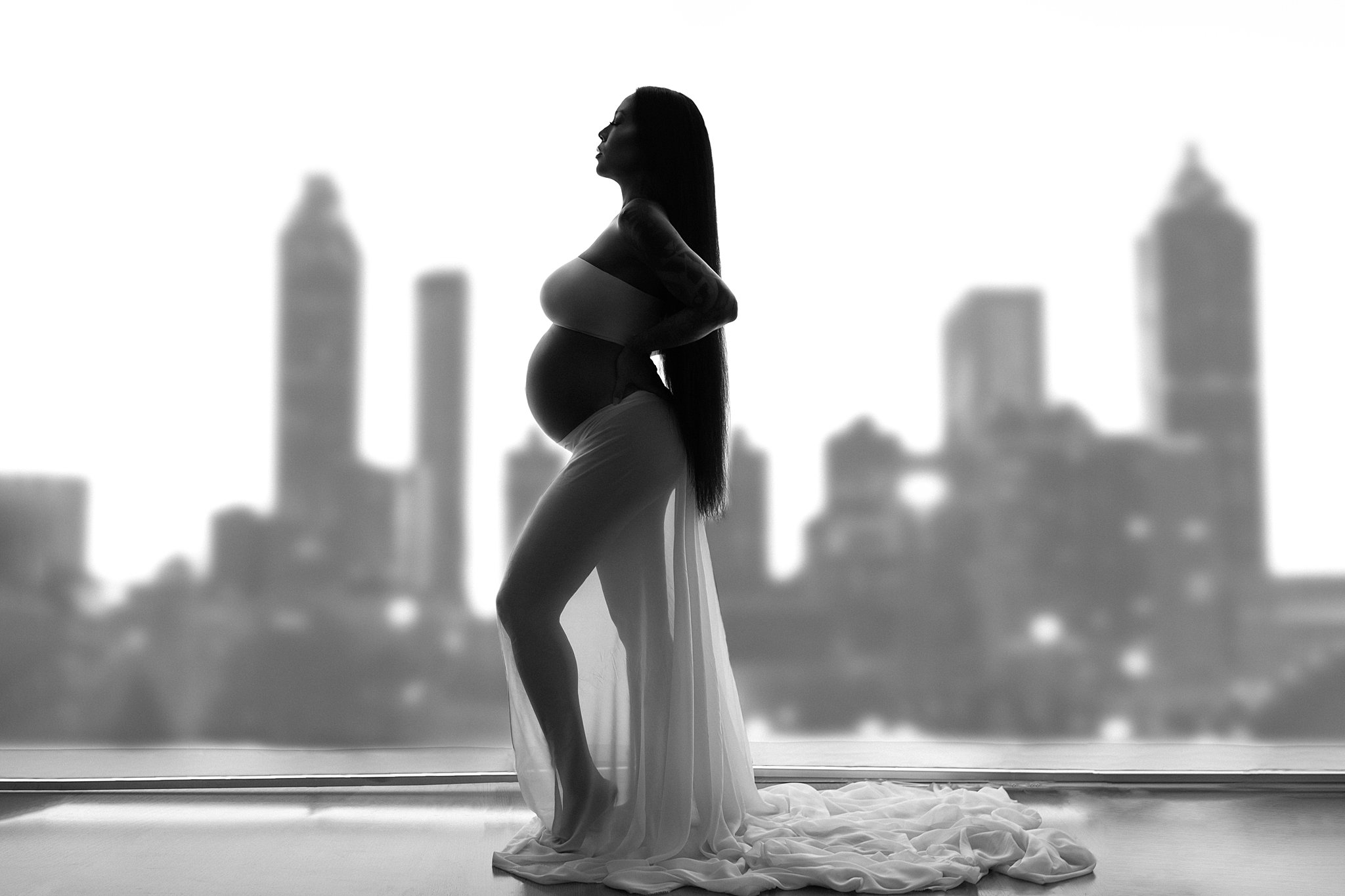 mom to be in a silhouette with the Atlanta skyline behind her Piedmont Maternity