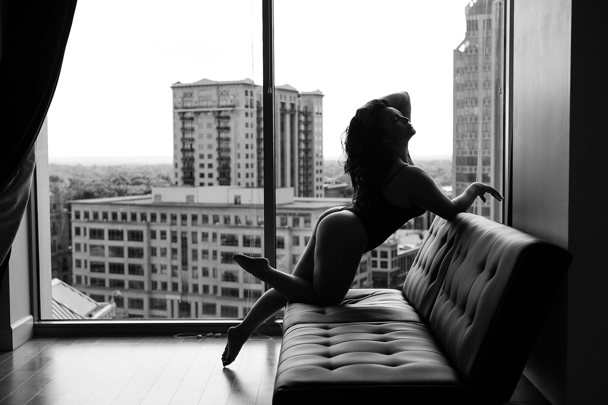 Silhouette of a woman in front of a window leaning over a couch