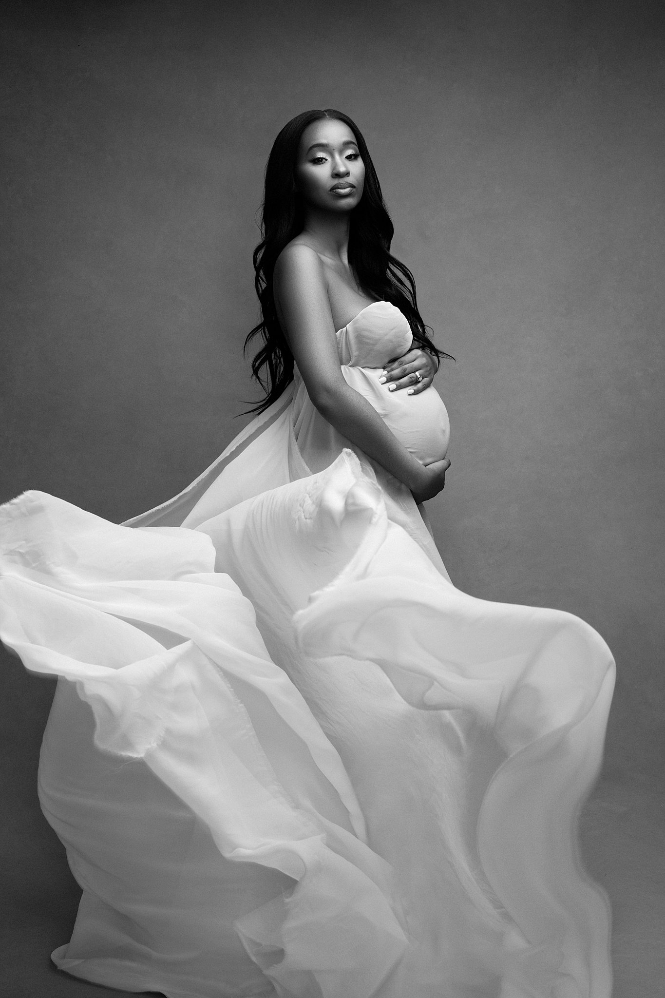 mom to be wearing long white maternity gown hold top and bottom of bump