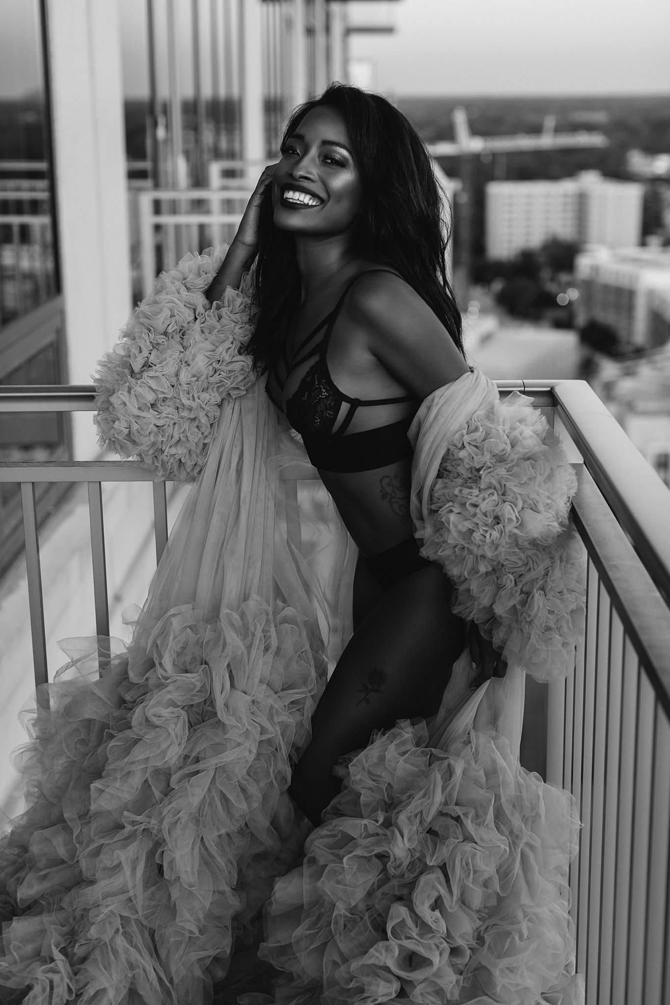 Woman stands on a balcony wearing black lingerie and velour gown med aesthetics miami