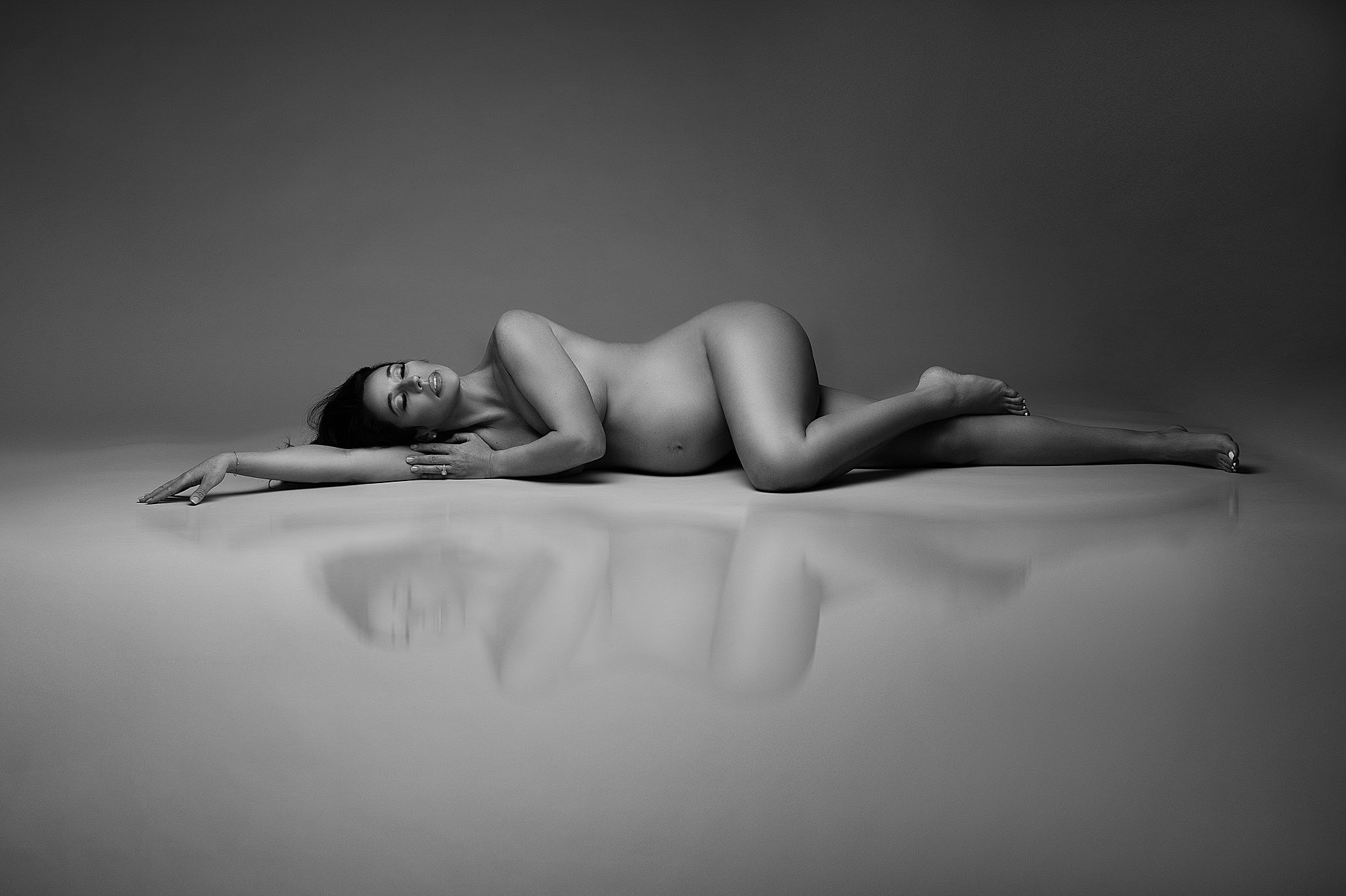 pregnant woman laying nude on the floor in a studio prenatal massage in miami