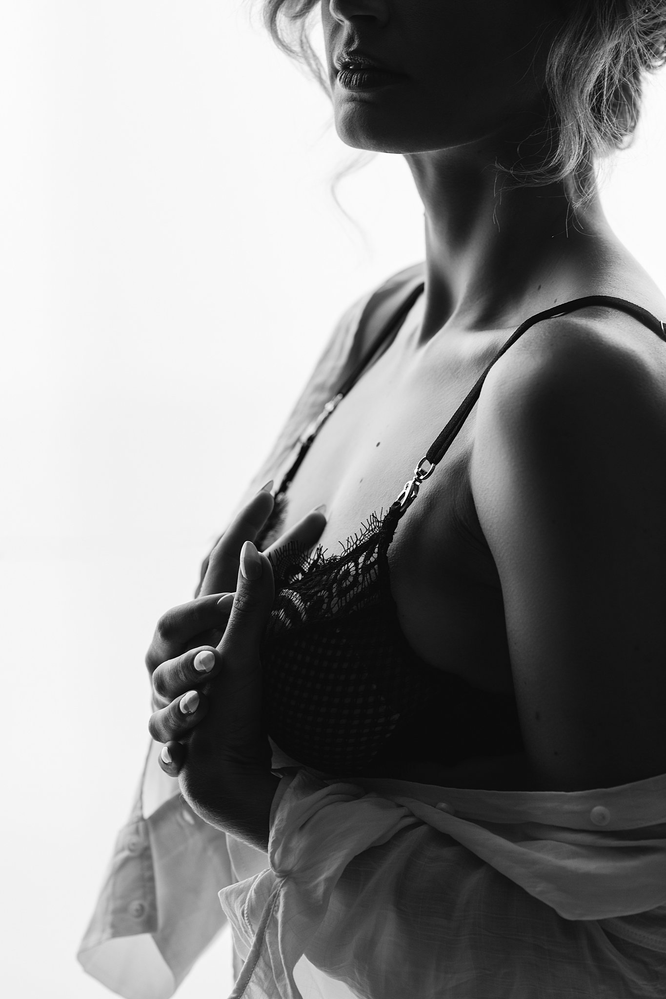 Silhouette of a woman in a black lace bra and white button down shirt off her shoulders