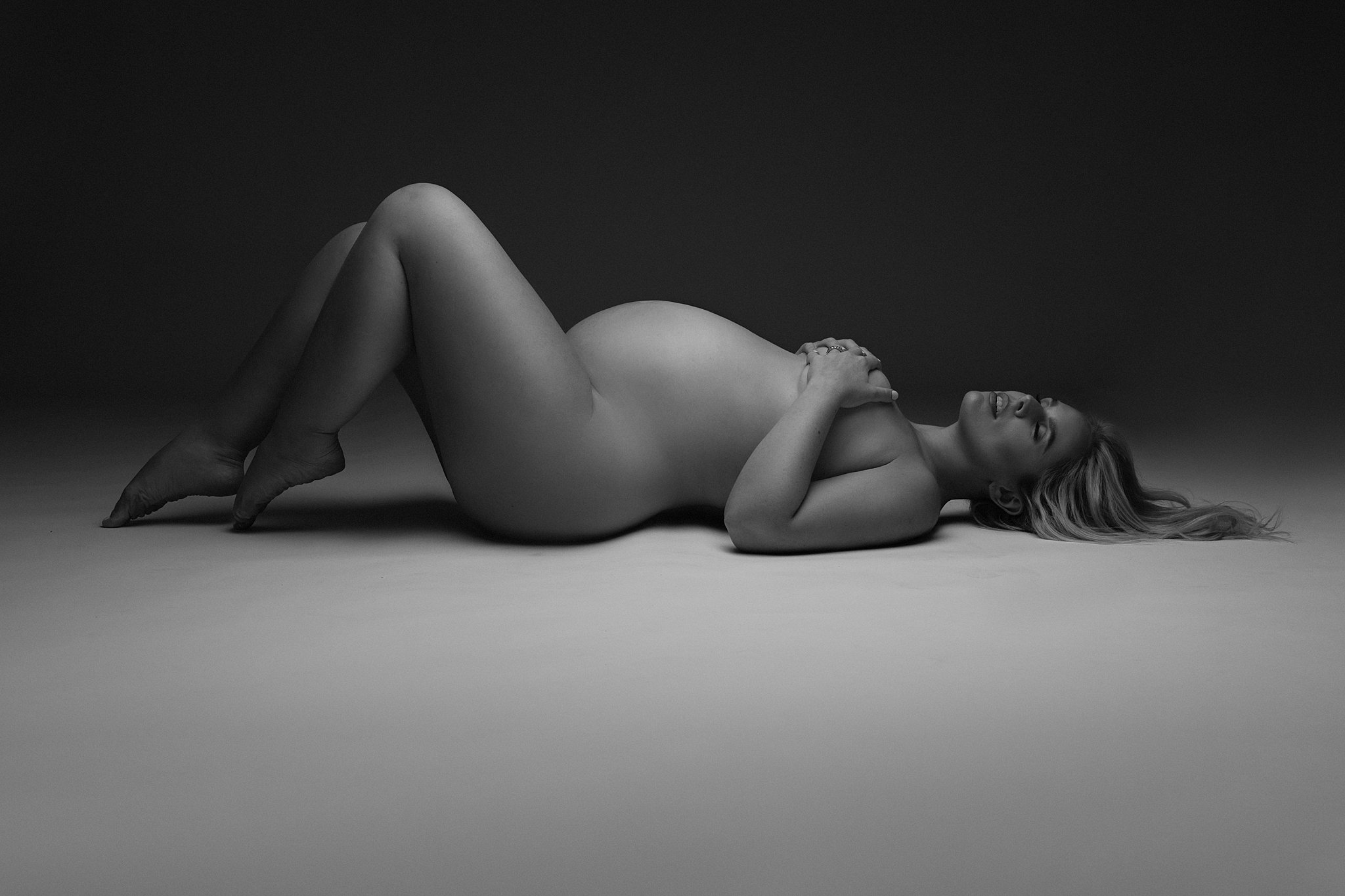 A mother to be lays on a floor of a studio with knees up Miami maternity center