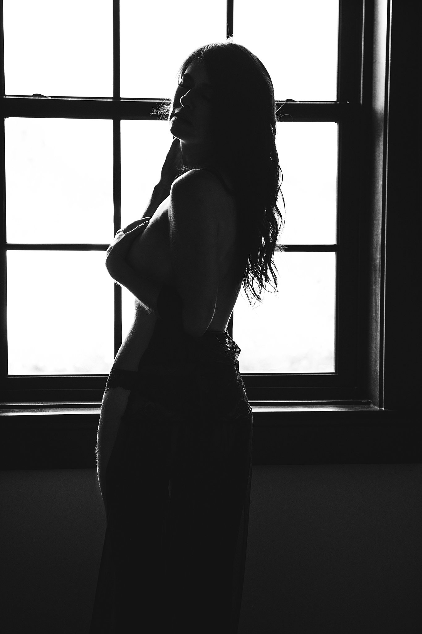 Silhouette of a woman standing inn front of a window wearing only a skirt kennesaw hair salons