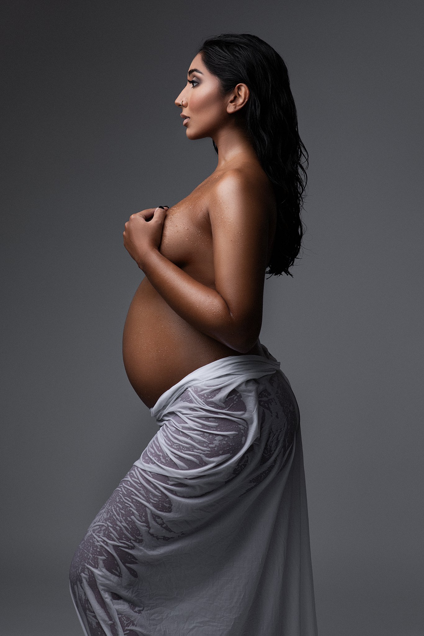 A pregnant woman stands in a studio wearing a wet fabric around her birthing center south florida