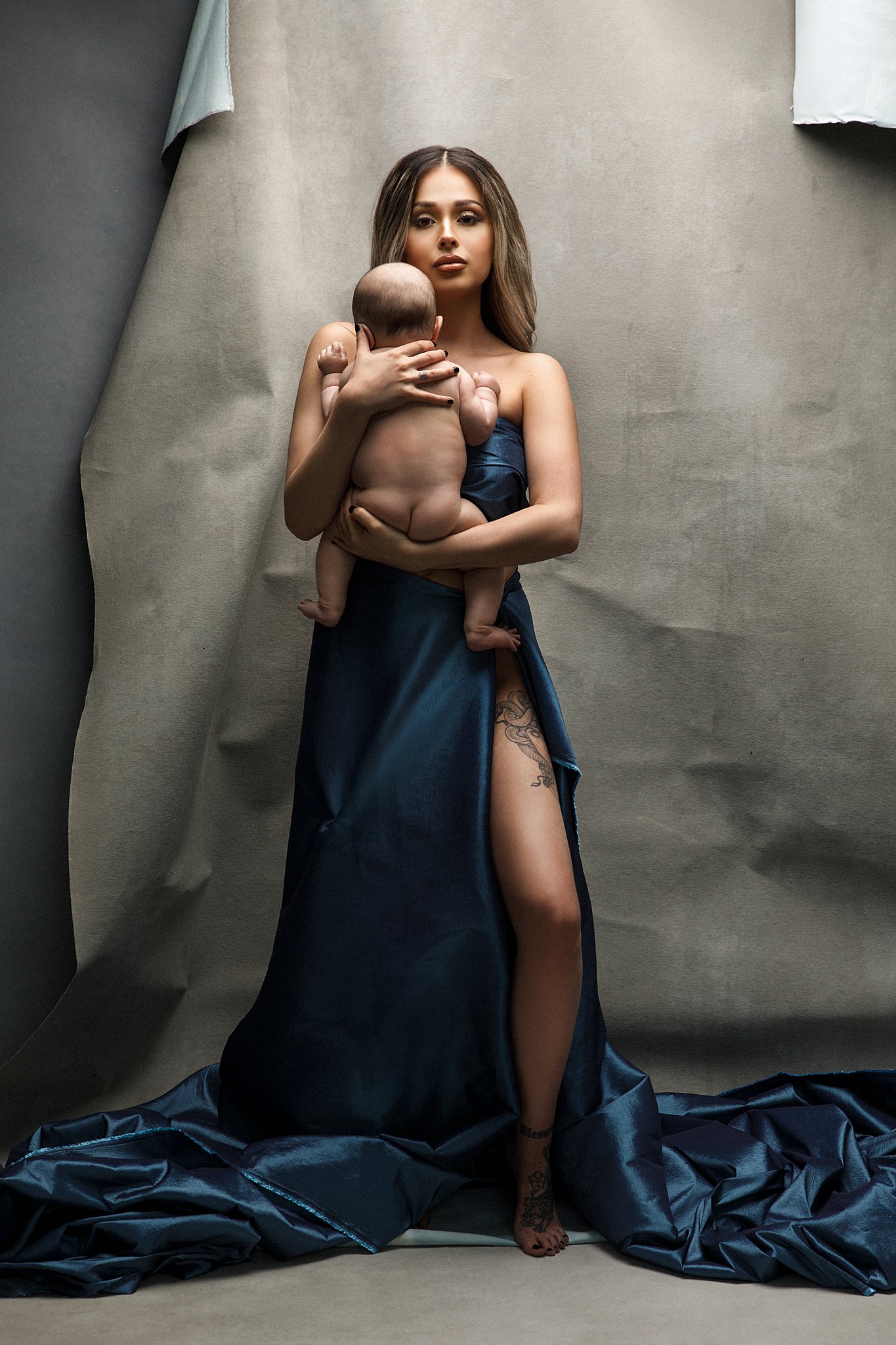 A new mother wears a blue fabric while holding her newborn baby against her chest namely newborns