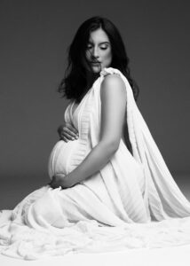 Side-angled maternity portrait with flowing gown and dramatic shadows