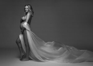 Dramatic maternity photo with flowing white fabric in studio