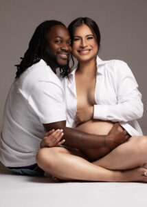 Studio photo of couple sitting and smiling in casual white shirts