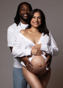 Intimate maternity photo of partner holding mom’s belly from behind