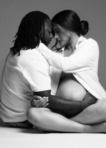 Black and white intimate maternity photo with couple sitting close