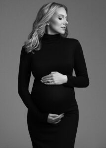 Studio maternity photo of pregnant woman in fitted black dress with soft lighting