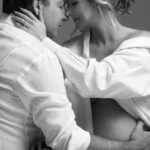 Artistic photo of couple seated on floor in casual white shirts and jeans
