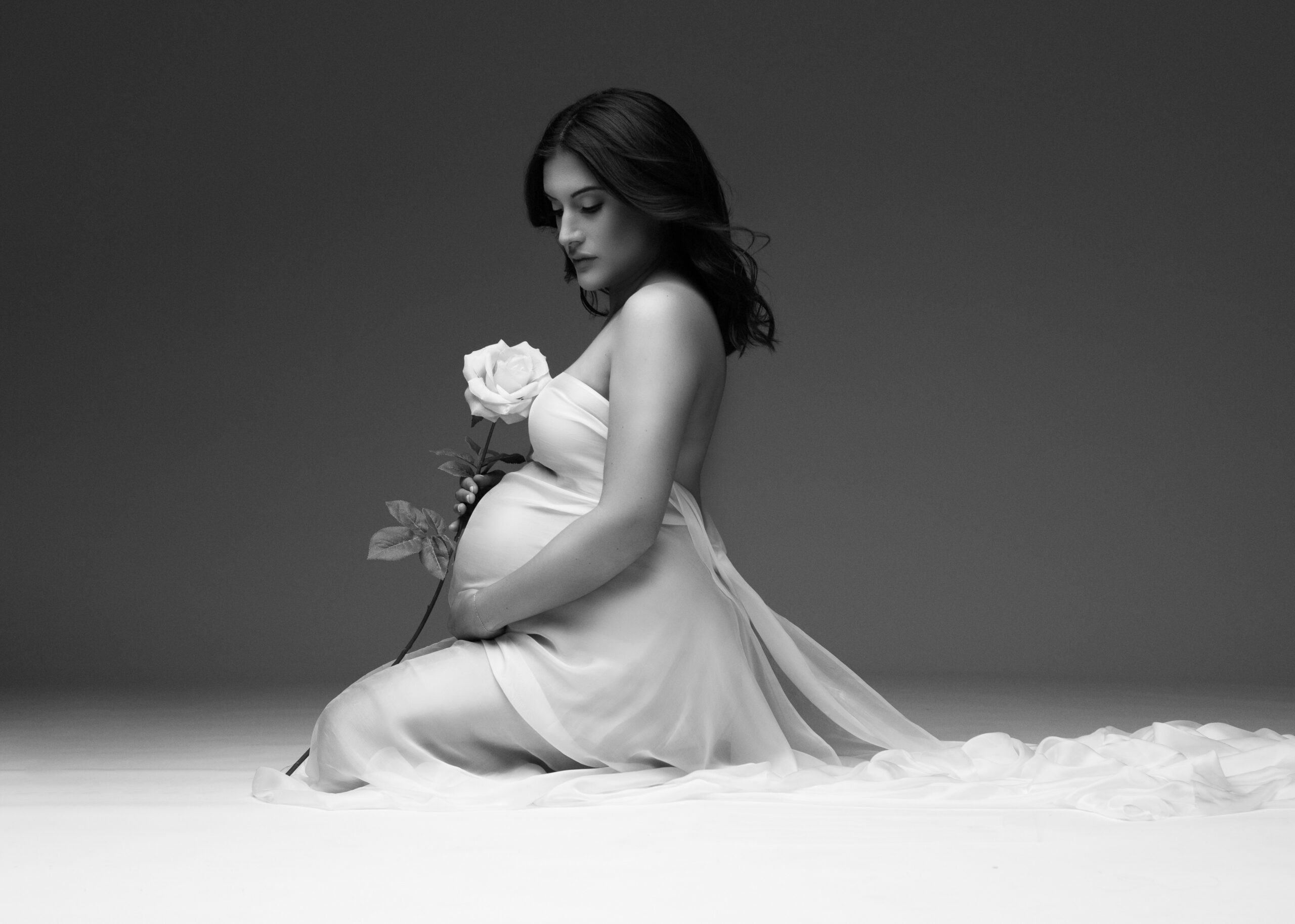 Black and white maternity portrait with draped white gown