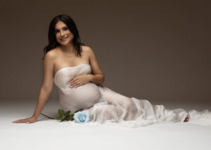 Studio maternity image with white fabric draping and soft lighting