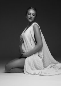 Glamorous studio maternity portrait in white fabric, highlighting baby bump